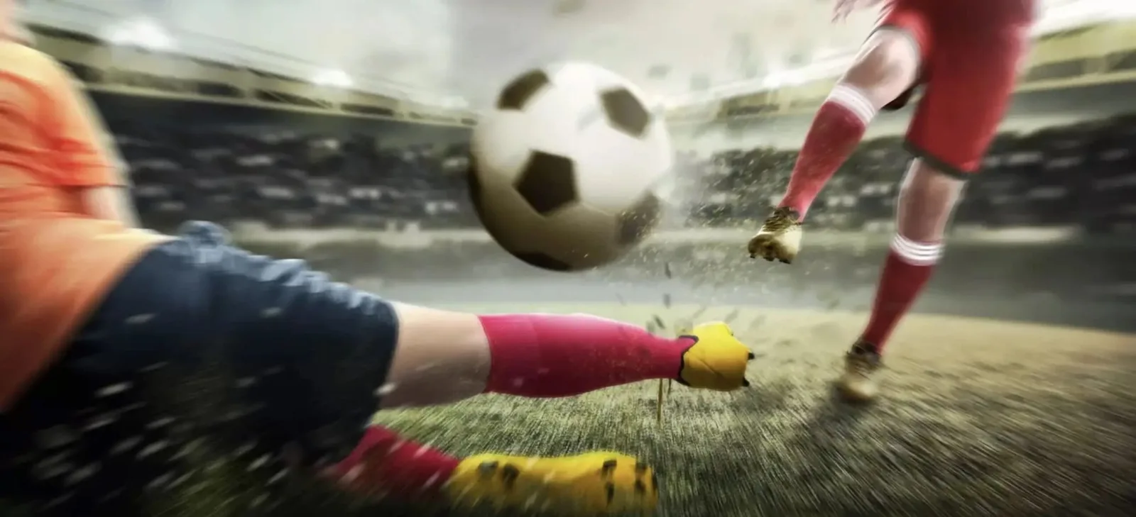 Dos jugadores disputando el balón a ras de césped, con la pierna estirada y tierra levantada alrededor.