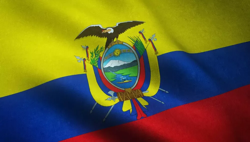 Bandera de Ecuador ondeando en primer plano, con el escudo nacional centrado.